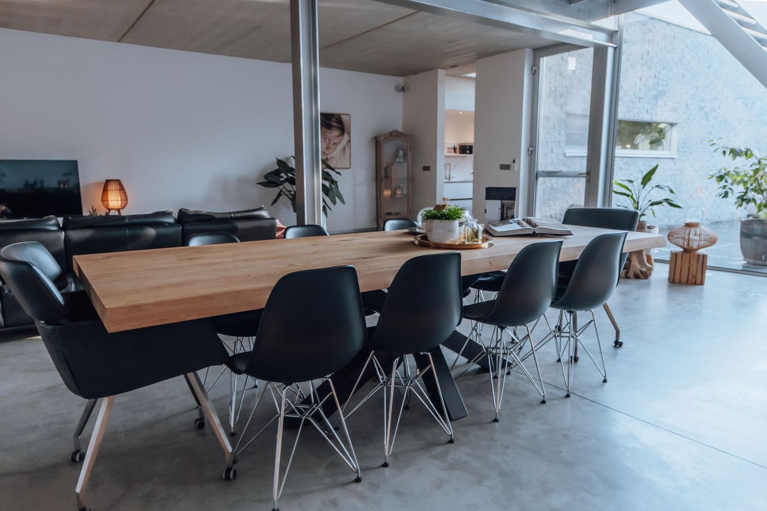 Moderne eetruimte met houten tafel, zwarte stoelen en natuurlijke verlichting door de grote ramen.
