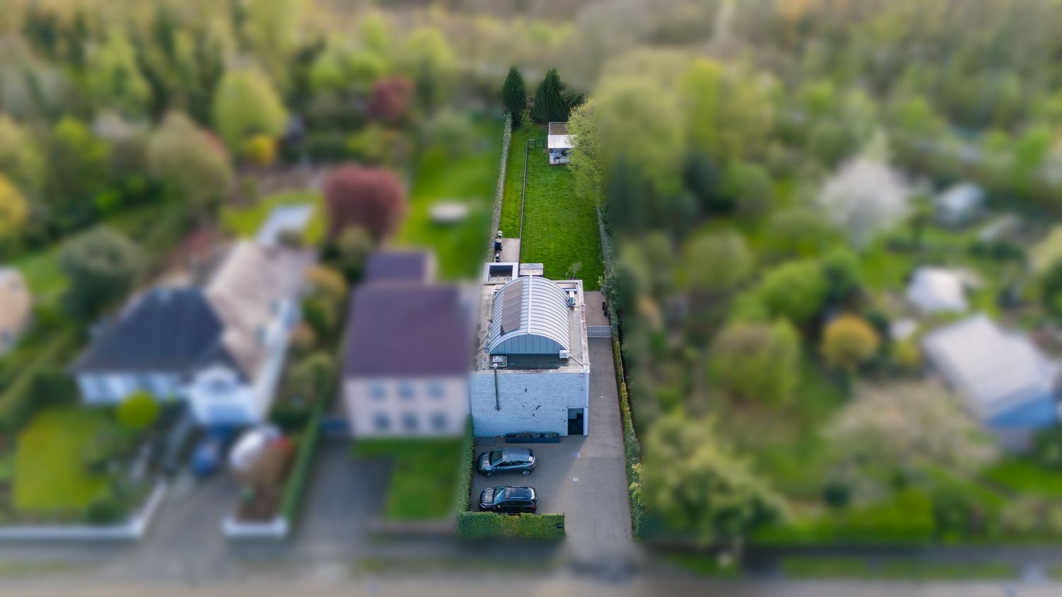 Luchtfoto van een voorstedelijke straat met huizen en auto's in een woonwijk.