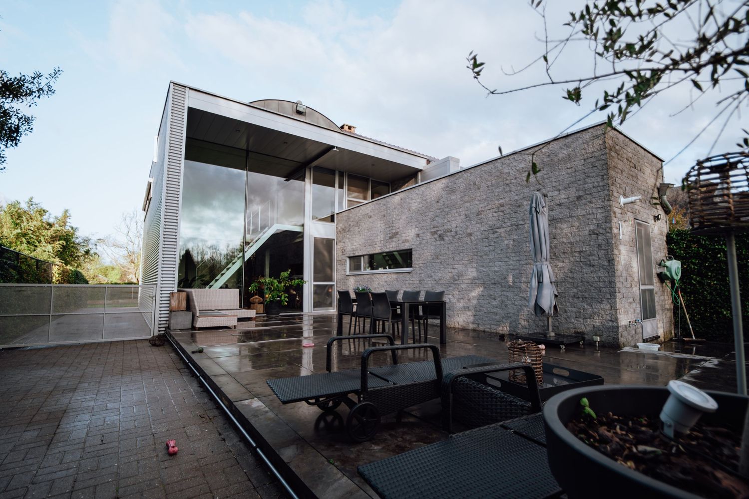 Eigentijds terras met glazen wanden en modern meubilair.