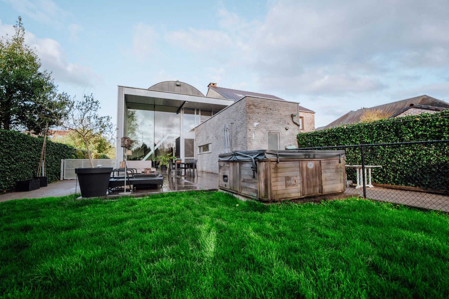 Luxe achtertuin met buitenkeuken, entertainmentruimte en goed onderhouden gazon.