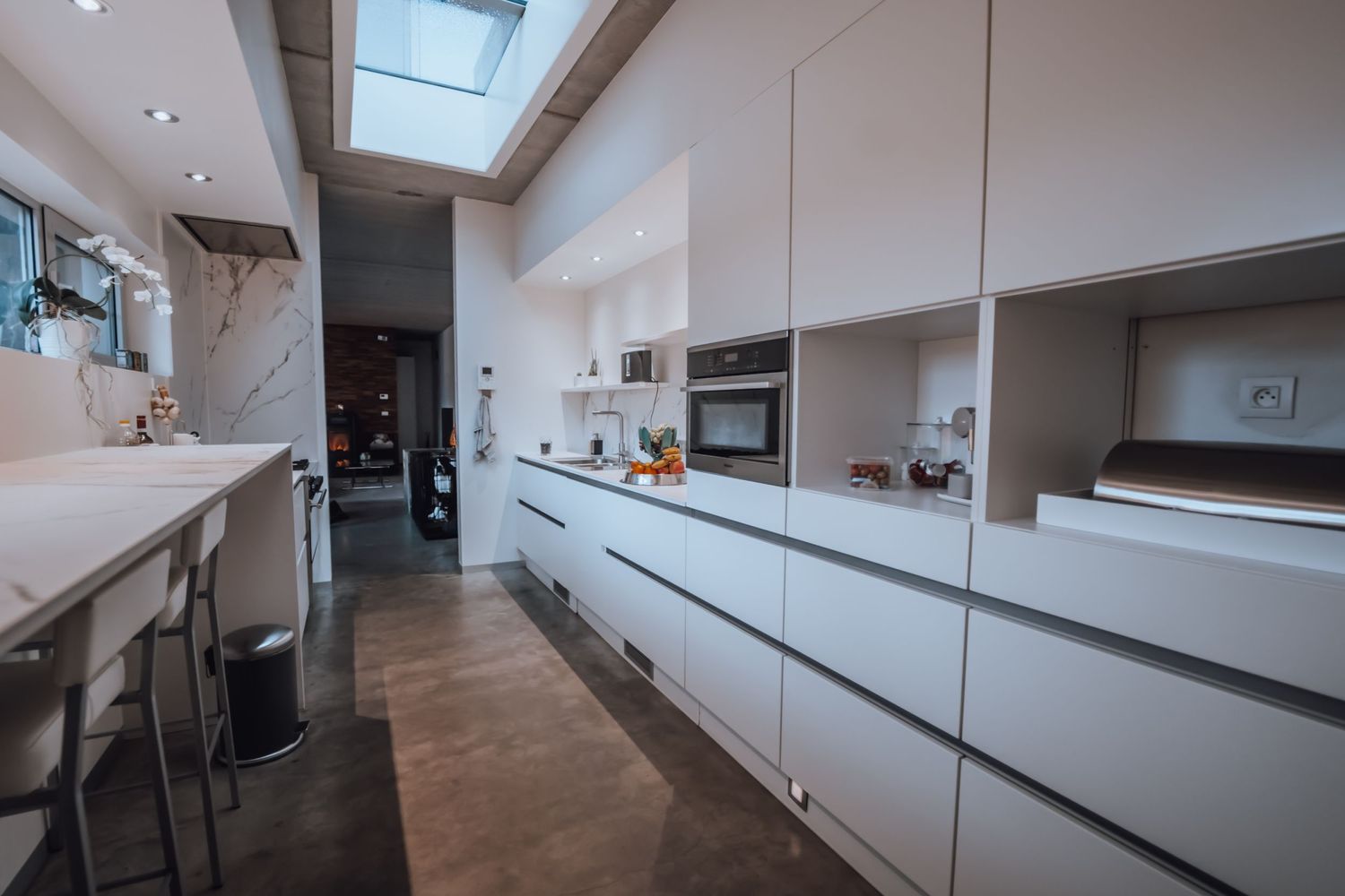 Strakke moderne keuken met witte kasten, dakramen en minimalistisch design.