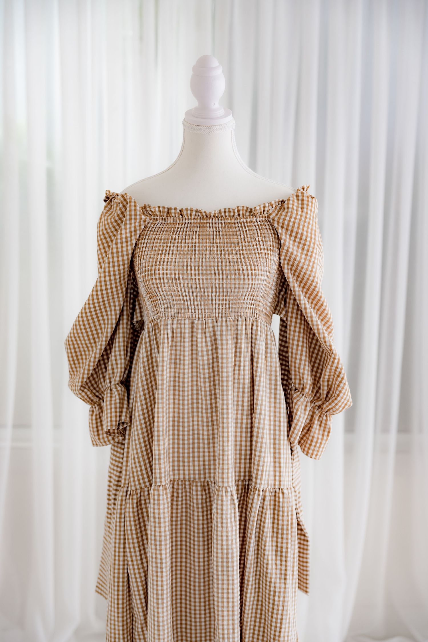 Close-up of off-shoulder gingham dress showing smocked bodice and puff sleeves.