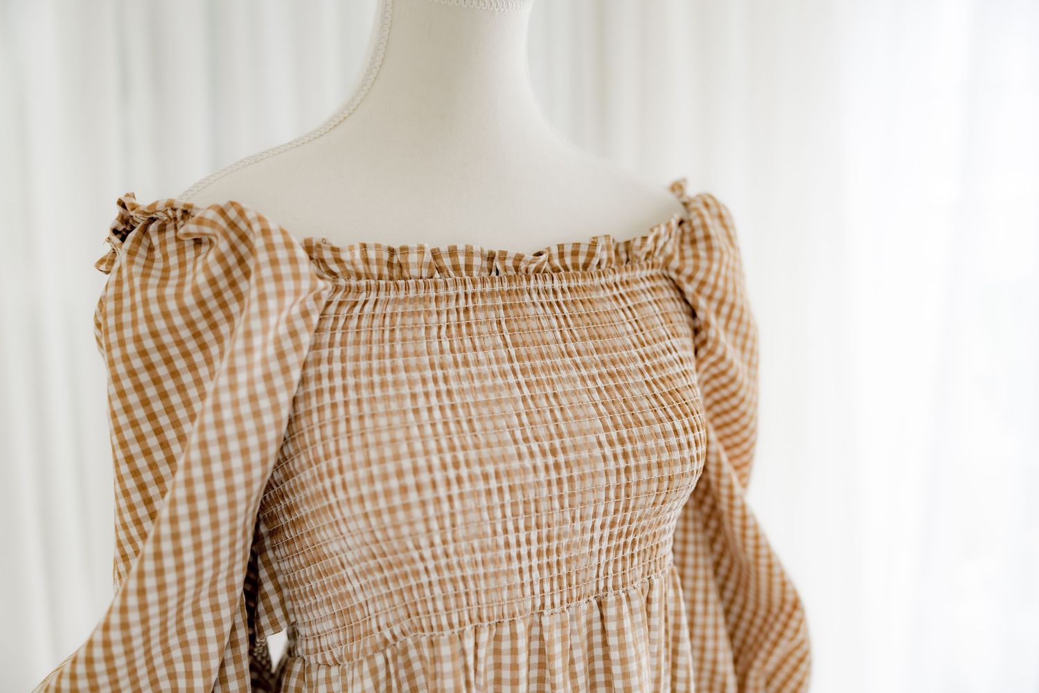 Close detail of smocked bodice and ruffle trim on vintage-style gingham dress.