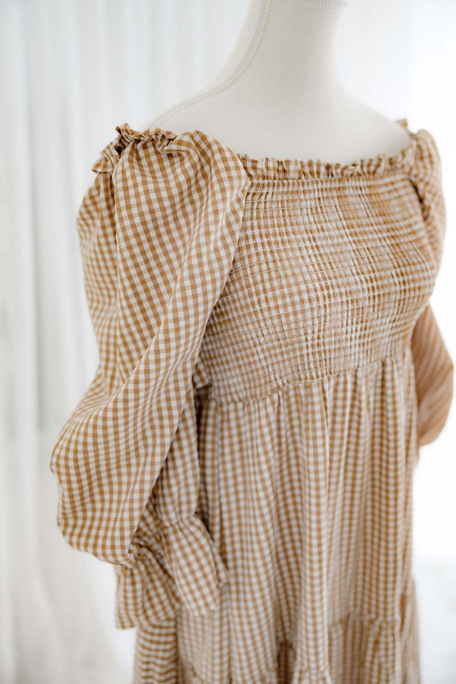 Side view of gingham dress showing puff sleeve detail and gathered waist design.