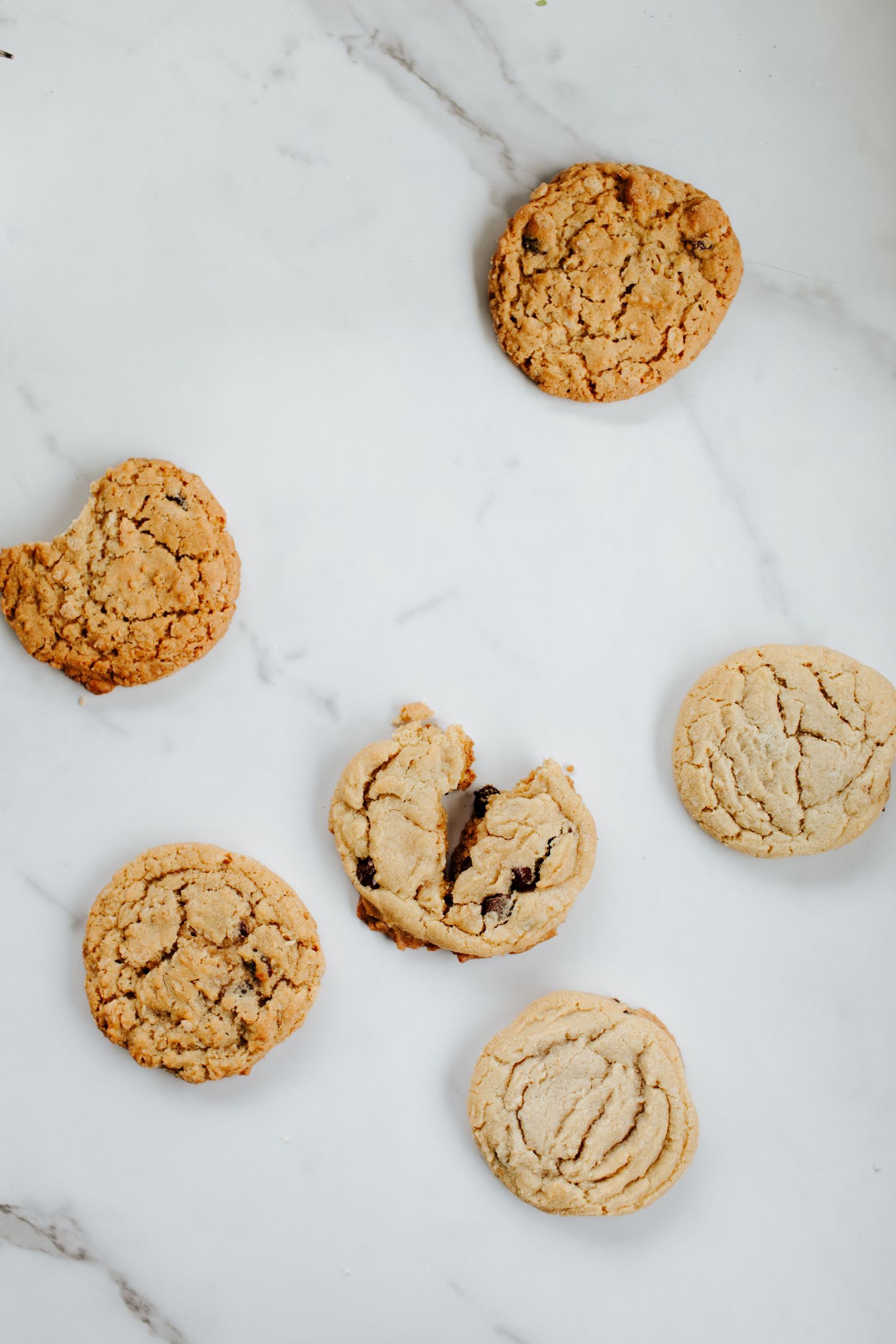 Golden brown cookies with crackled tops arranged on white marble surface.