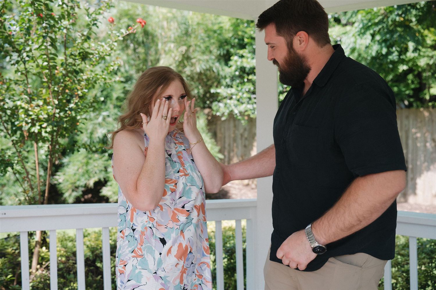 An emotional moment unfolds between two people on a white porch with lush greenery in the background.