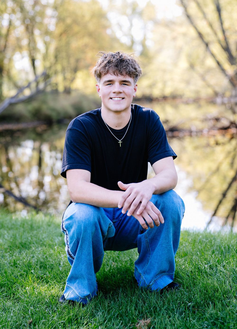 Casual outdoor portrait by a pond with natural lighting and reflections.