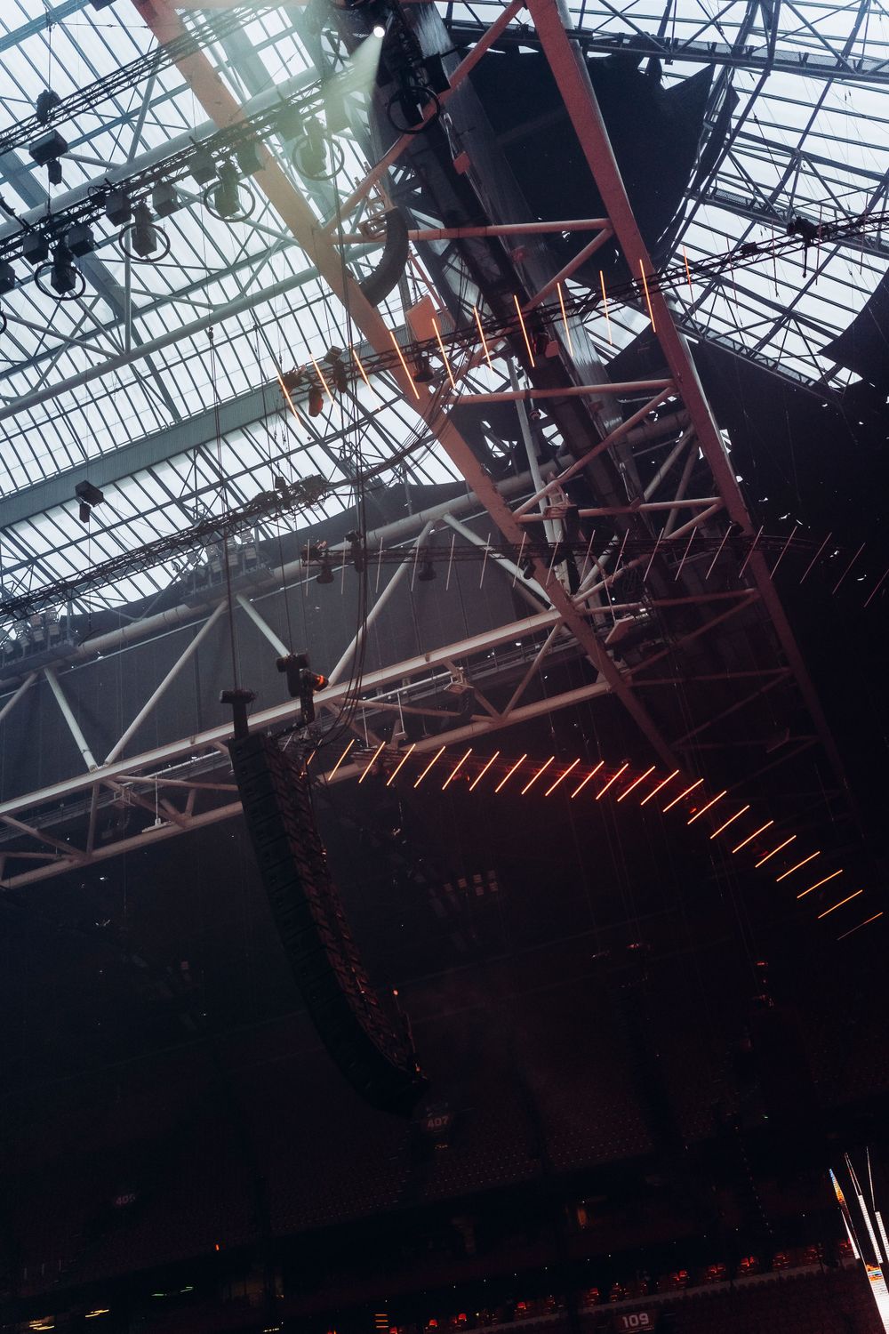 Low-angle view of industrial stage rigging and support structures at indoor venue.