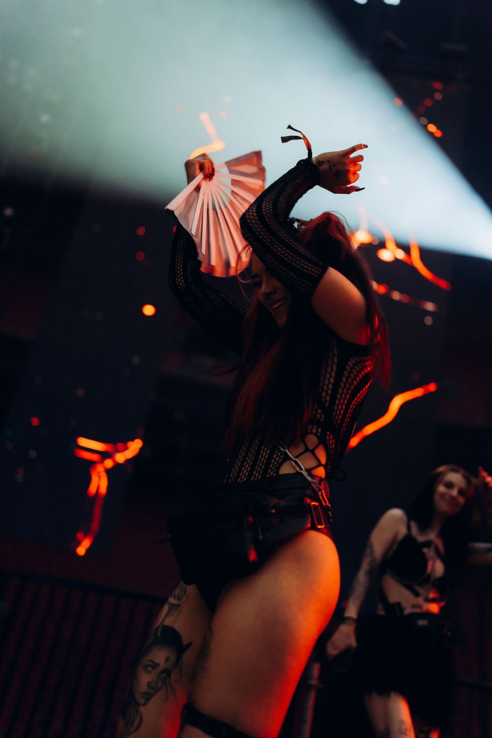 Dramatic stage performance with fan costume detail and red lighting effects.