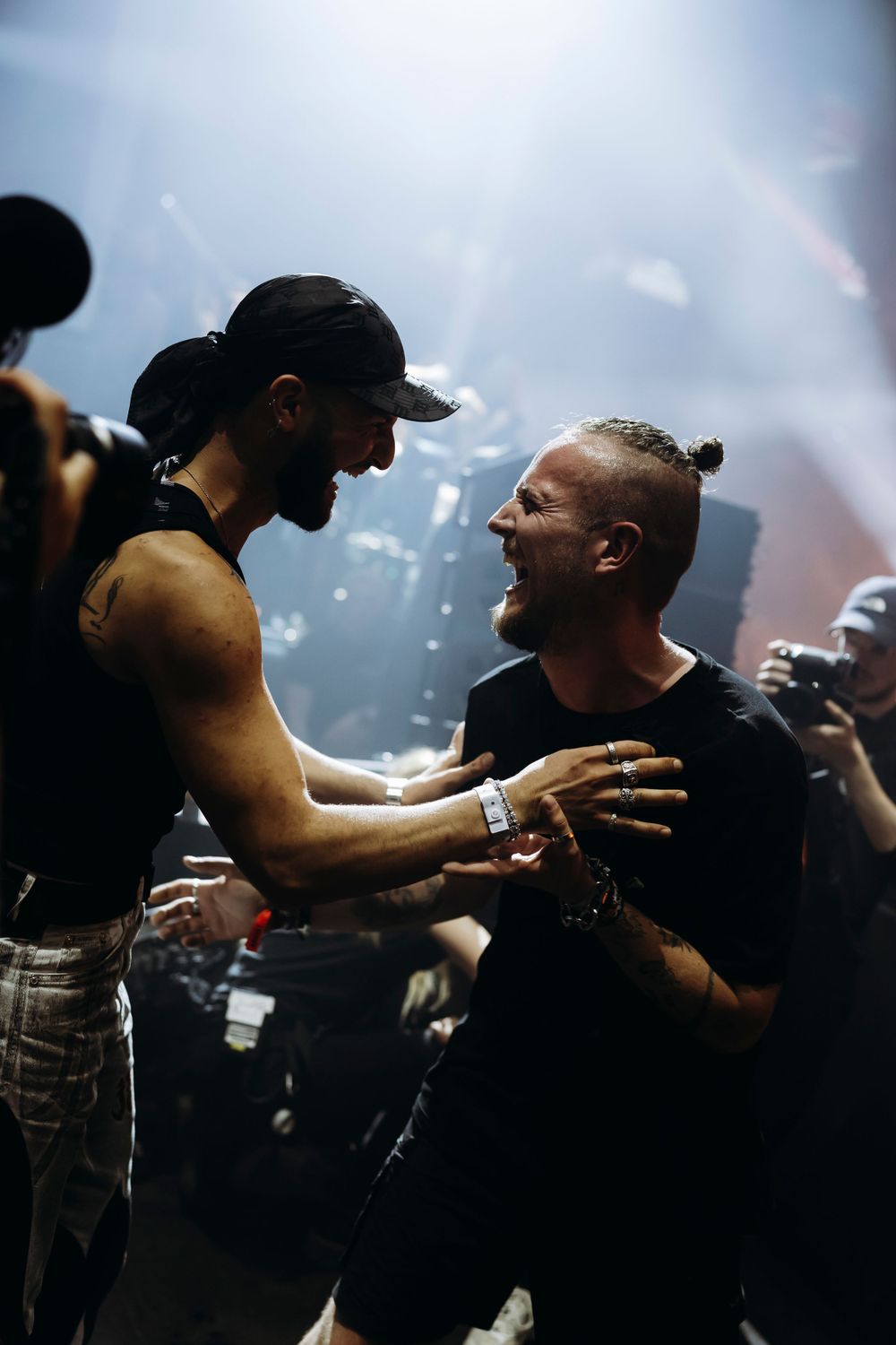 Silhouetted figures embracing during an emotional moment at a concert venue.