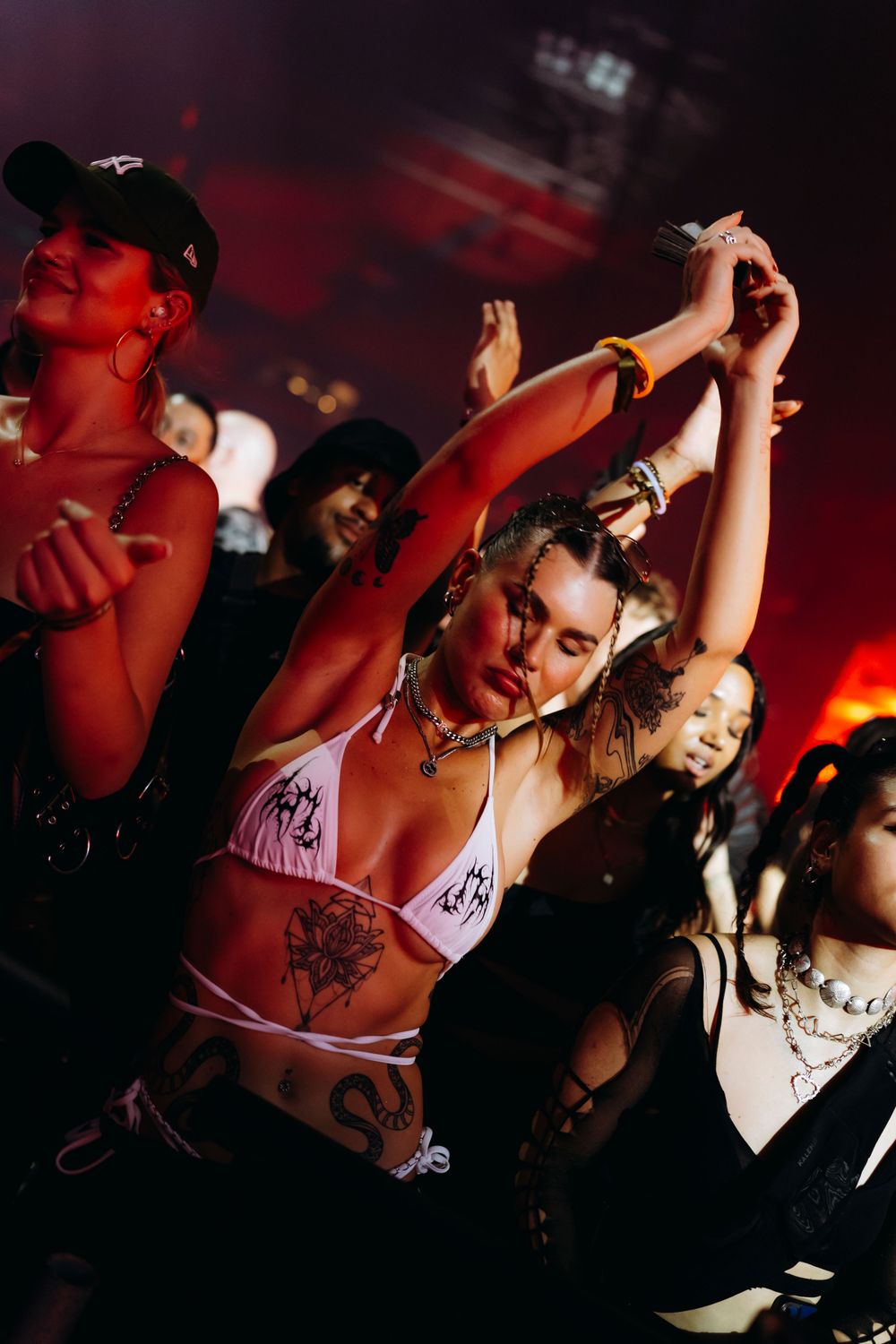 Energetic crowd with raised arms dancing at a nighttime music event.