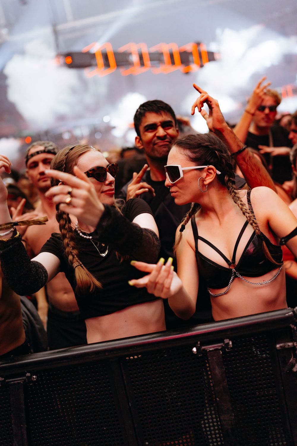 Festival crowd reaching over barrier at front of stage during concert.