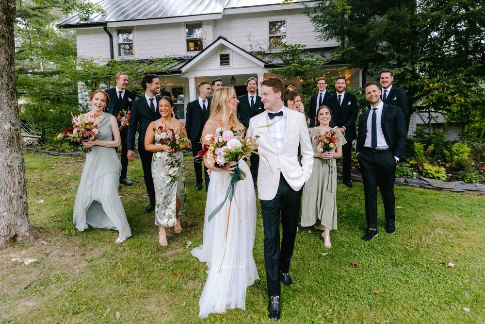 Wedding party poses on lawn with bride and groom in white attire.