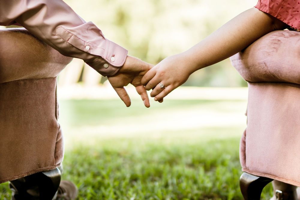 Close-up of hands reaching towards each other in soft outdoor lighting.