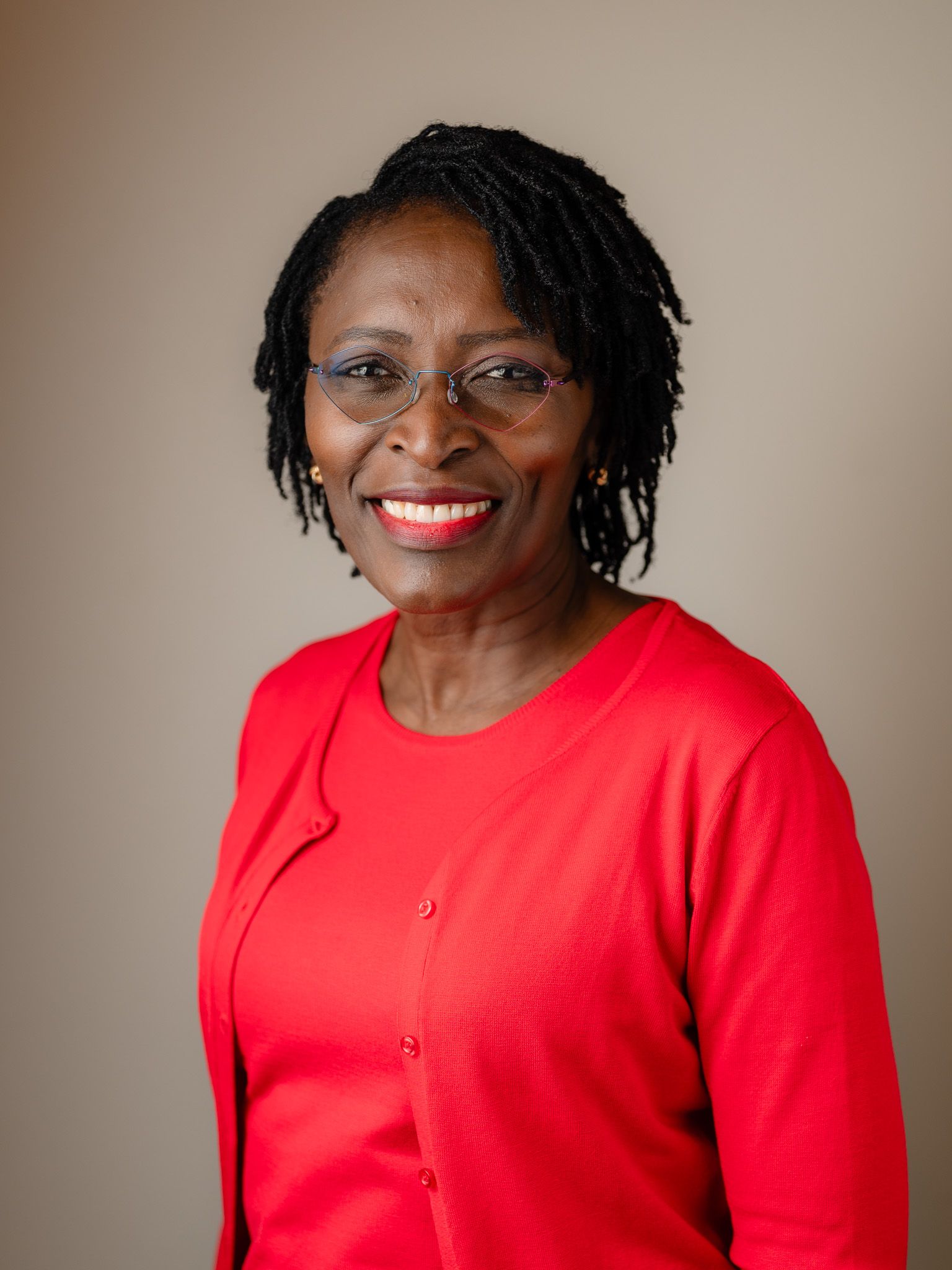 Professional headshot of person in bright red sweater against neutral backdrop.