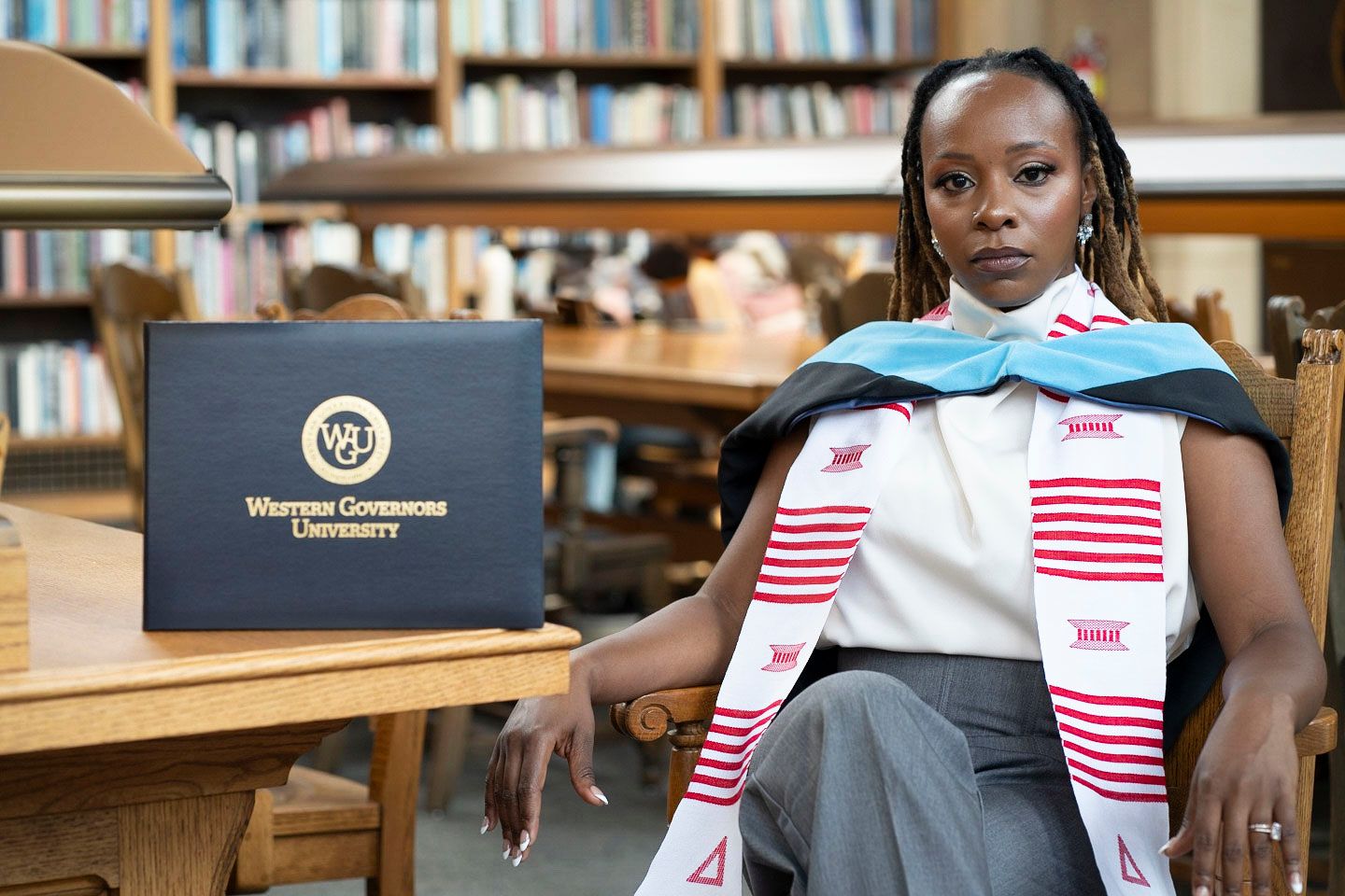 Student sitting in library with backpack and Western Governors University materials.