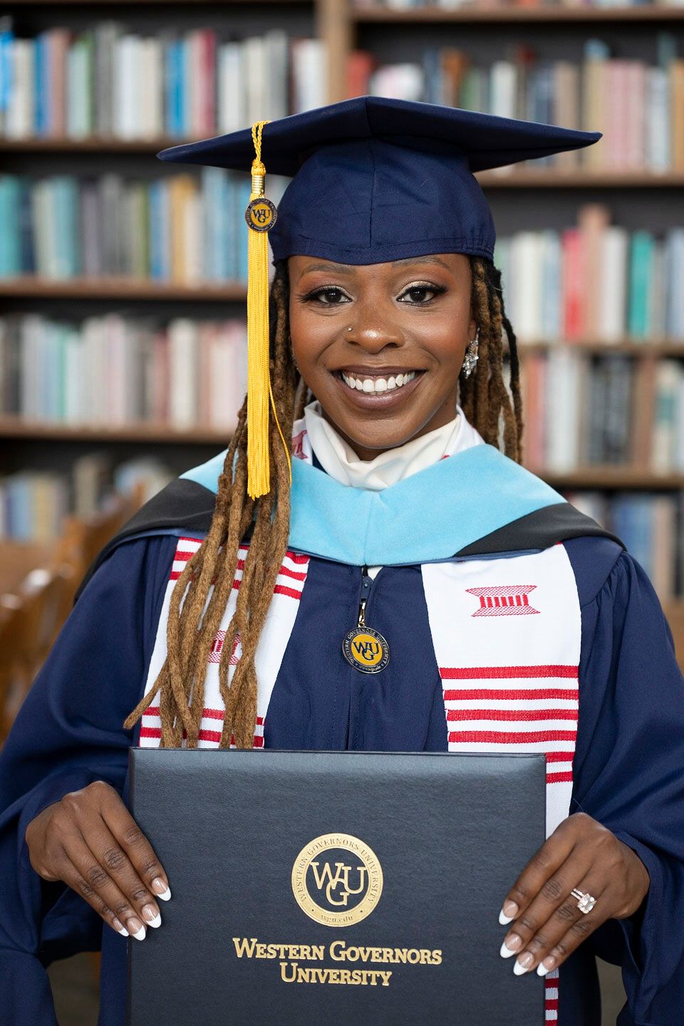 Graduate in academic regalia holding diploma from Western Governors University.