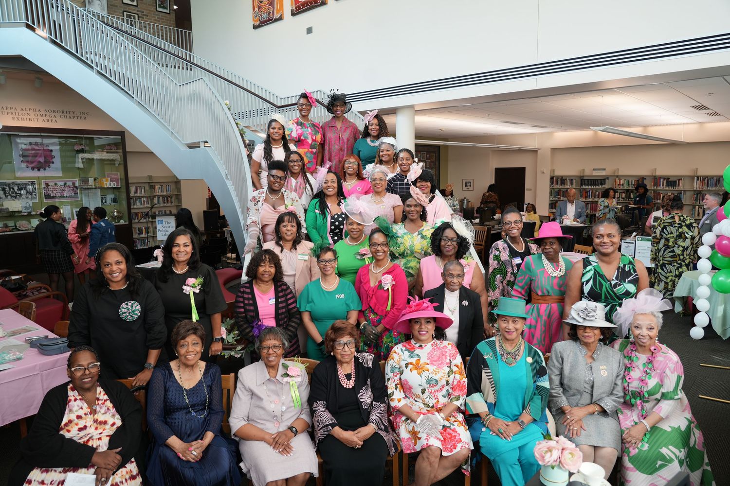 A group of people dressed in pink, green, and white gather together for what appears to be a community event or celebration.