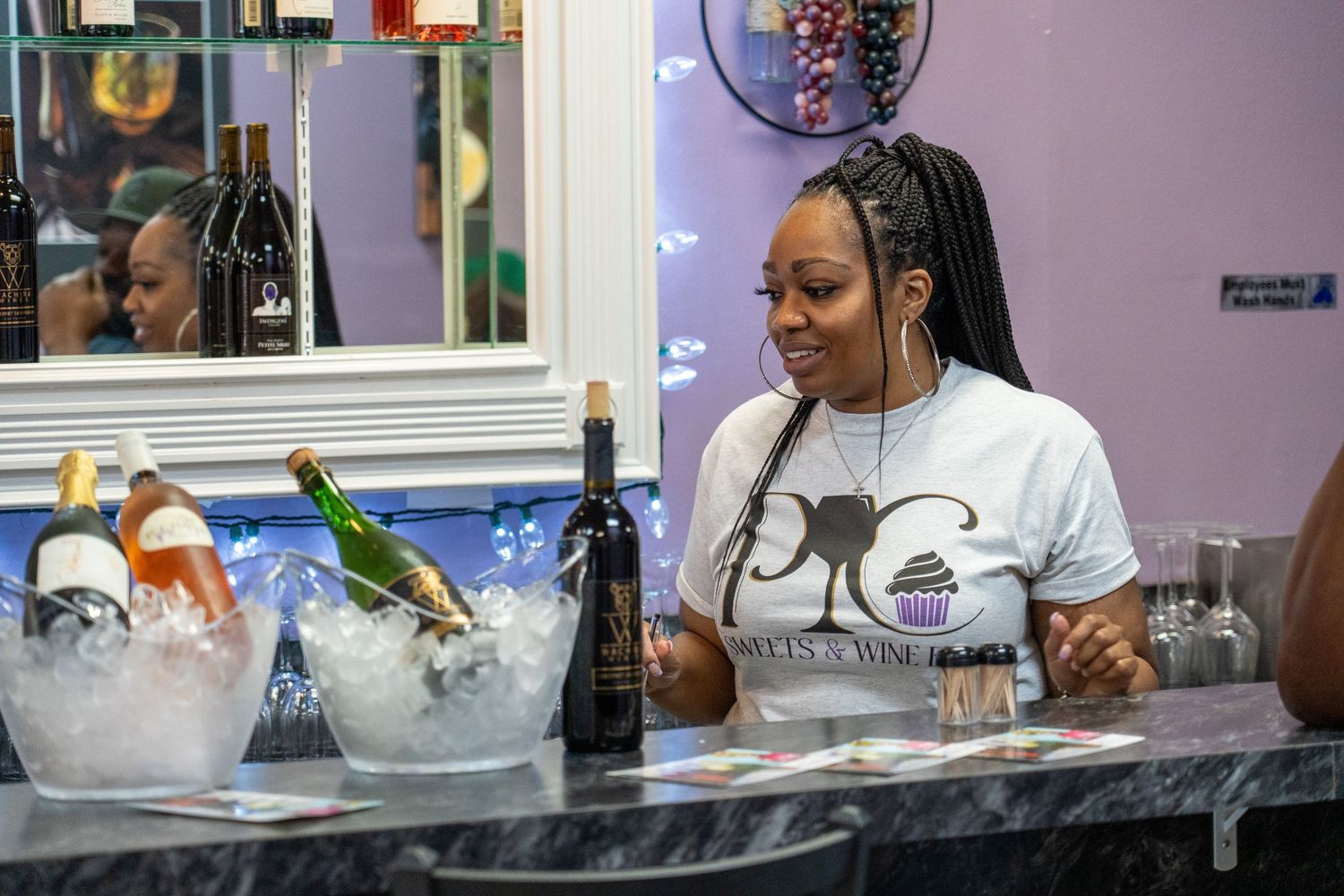 Someone working behind a bar counter with bottles of wine chilling in ice buckets at a restaurant or lounge.