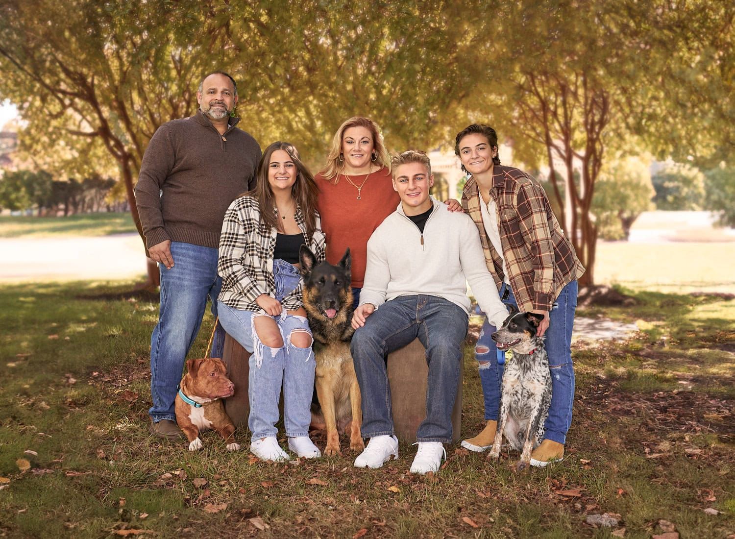 Perry Hall family of five with three dogs sitting among trees at a local park
