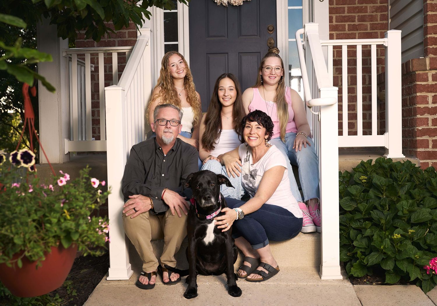 Parents with three teenage girls sitting on front steps of  their Perry Hall Maryland home