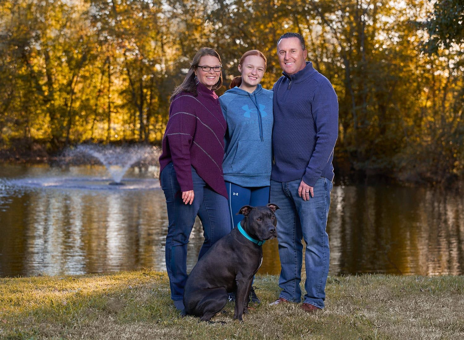 Parents and 13-yr-old daughter in casual attire in front of a pond with a center fountain at Kinder Farm Millersville MD