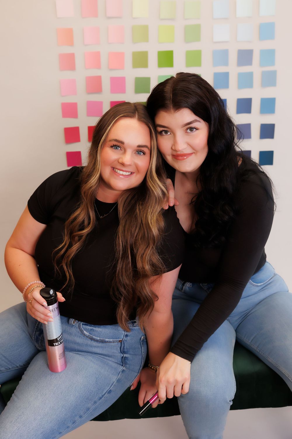 Two people sitting together in front of colorful paint swatch wall.