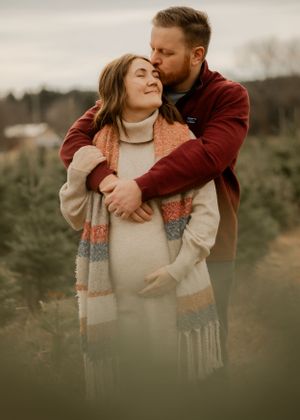 A couple shares an intimate moment outdoors during a maternity photoshoot.