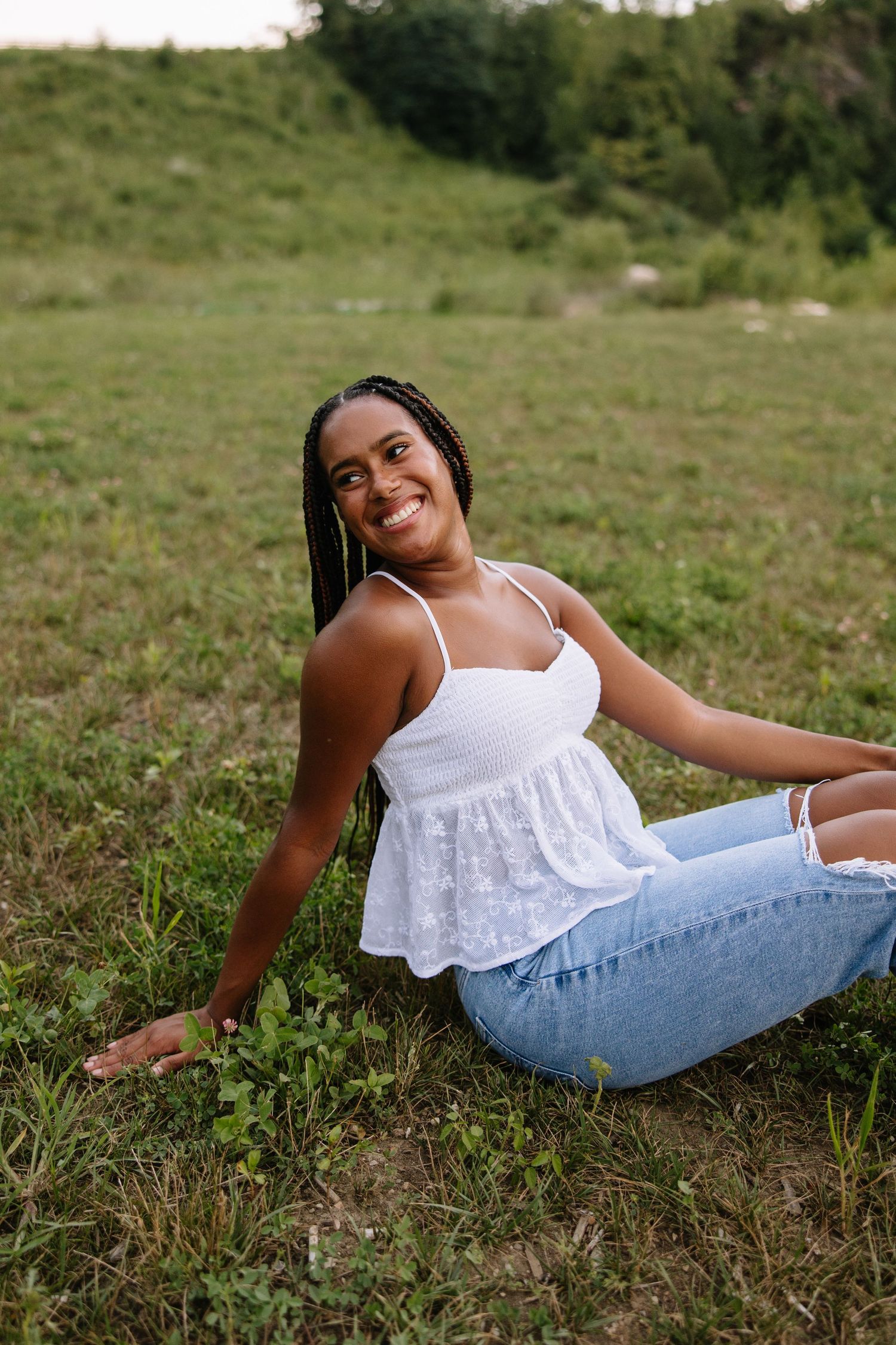 Backlit portrait of woman in white dress during golden hour in field.