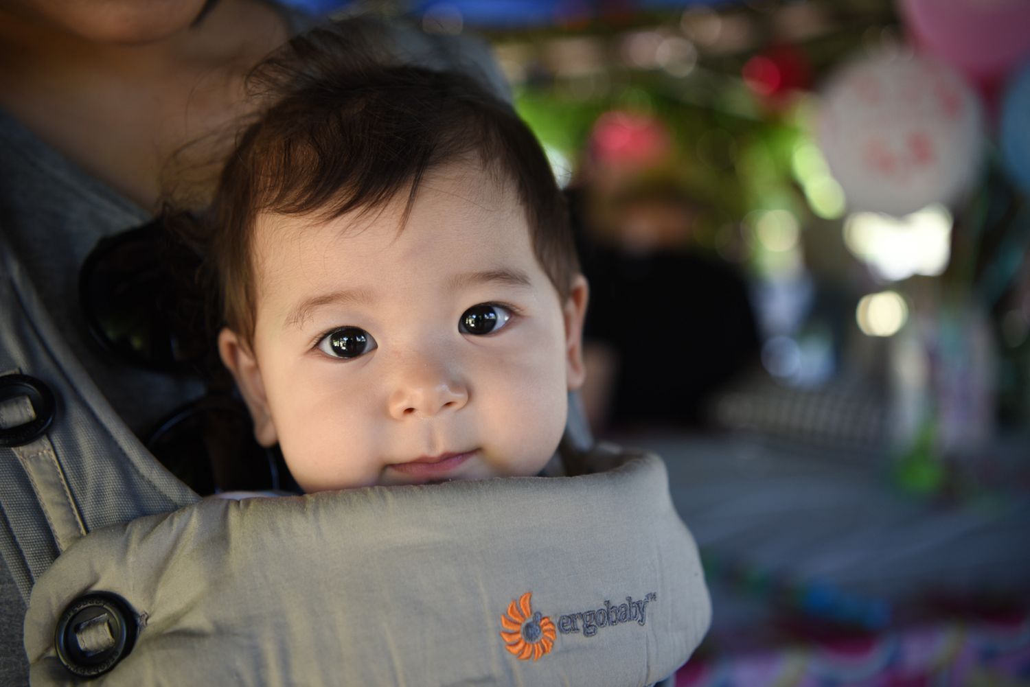 Baby in a carrier on a birthday party.