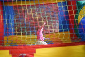A bouncy castle with colorful walls and a blue netting top provides an exciting play space for kids at birthday party.