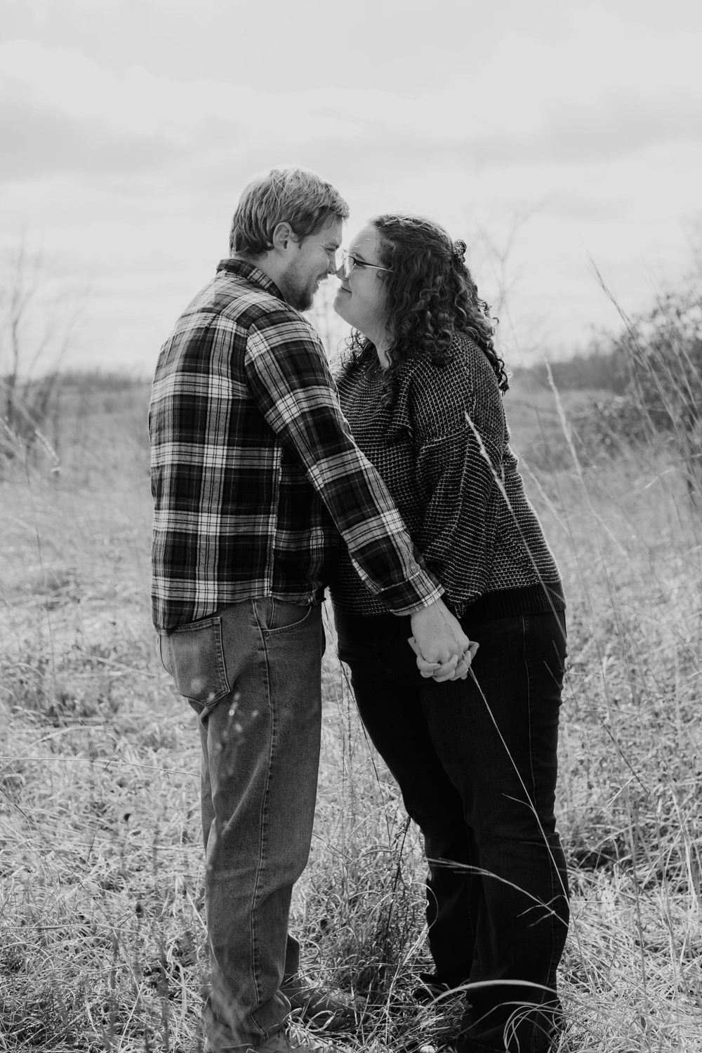 A romantic black and white photo of a couple sharing an intimate moment in a field.