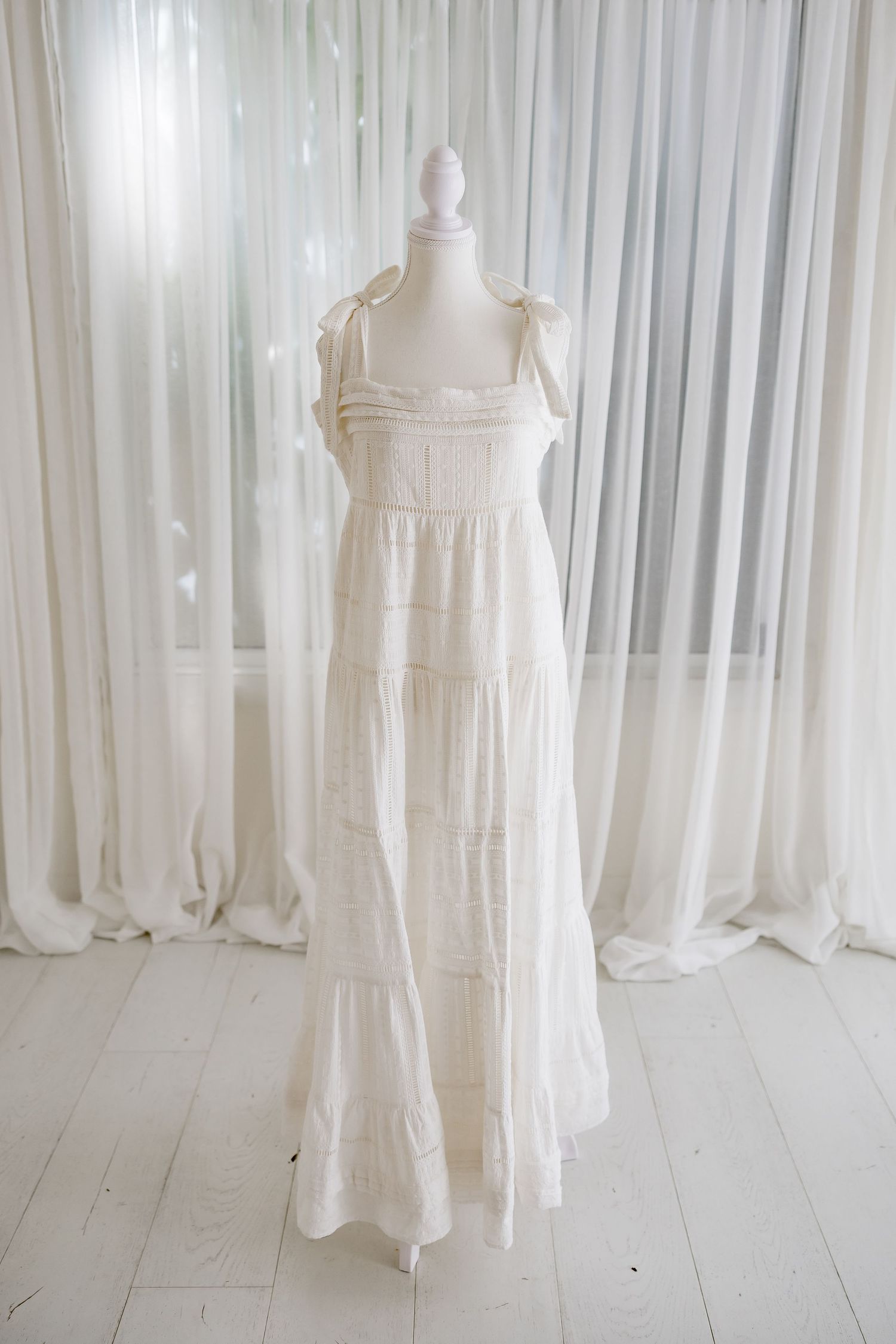 White tiered cotton maxi dress with shoulder ties displayed on mannequin.