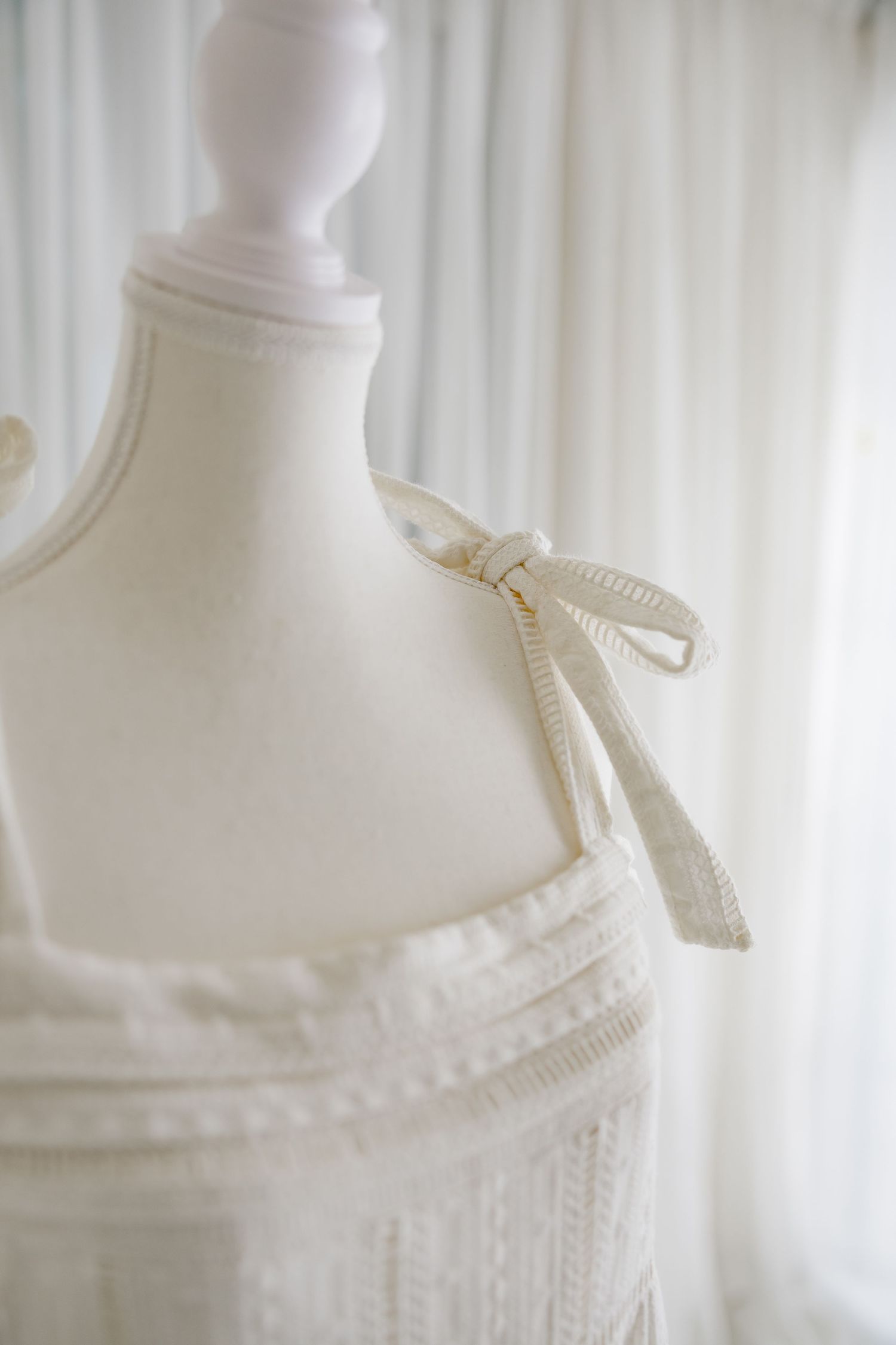 Close-up detail of cream ribbon tie and gathered neckline on vintage dress bodice.