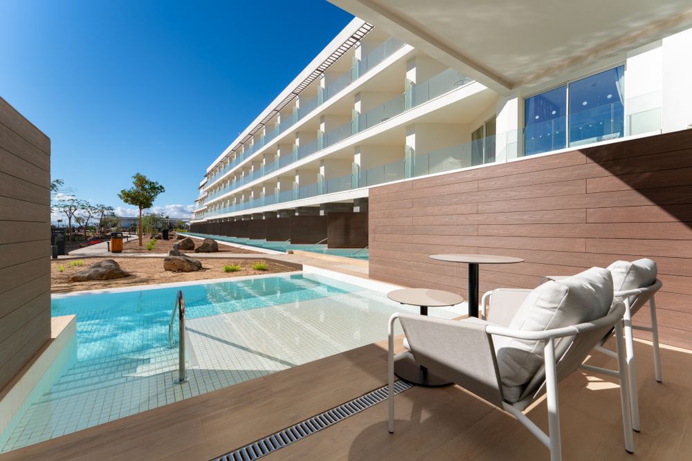 Luxury hotel terrace with private plunge pool and lounge chairs under modern architecture.