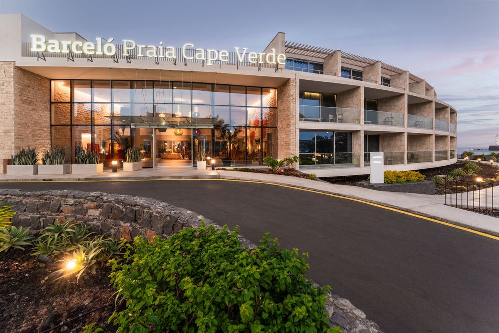 Modern Barcelo Praia Cape Verde hotel exterior with illuminated entrance and terraced architecture at dusk.