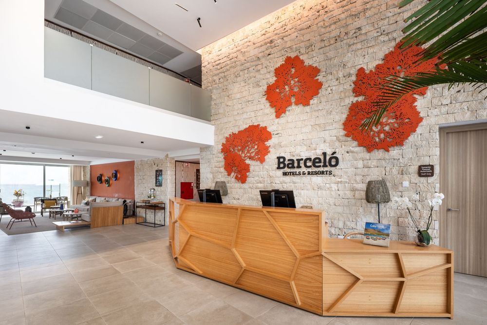 Modern office lobby with geometric wooden reception desk, exposed brick walls, and orange accent wall decor.