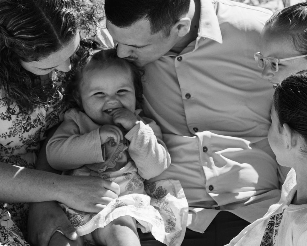 Heartfelt black and white outdoor session, parents and children sharing gentle connection.