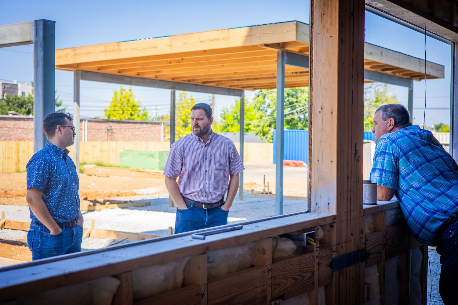 Three people having discussion at outdoor covered counter area.