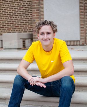 Portrait on brick building steps wearing yellow Nike t-shirt and jeans.