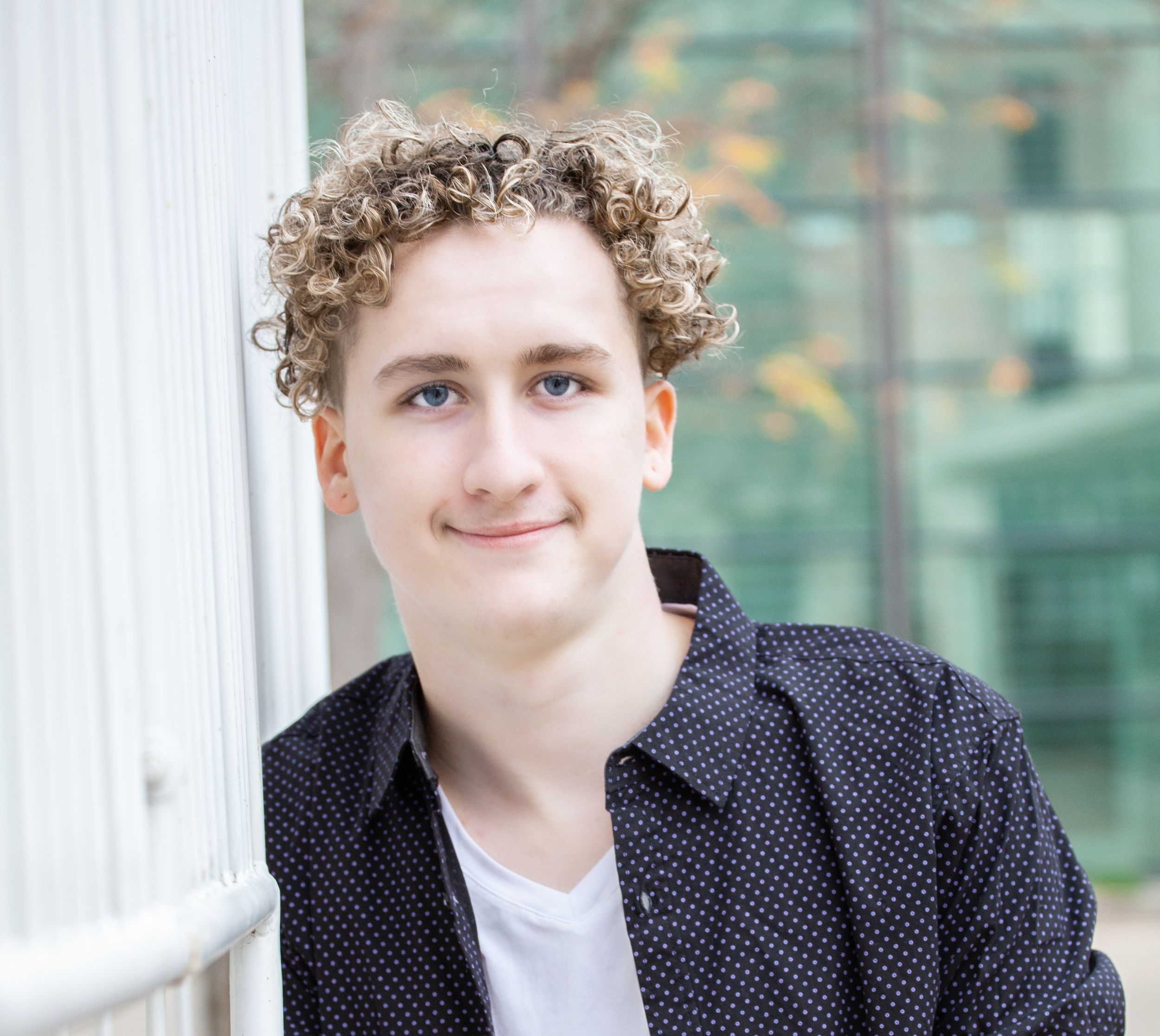 Close-up portrait showing curly hair and polka dot jacket against blurred background.
