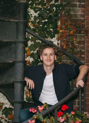 Autumn portrait on spiral staircase with red flowers and ivy covered brick wall.