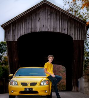 Yellow Pontiac sports car parked under rustic covered bridge.