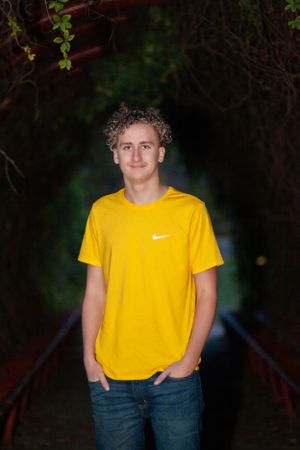 Portrait in bright yellow Nike shirt against dark tunnel background.