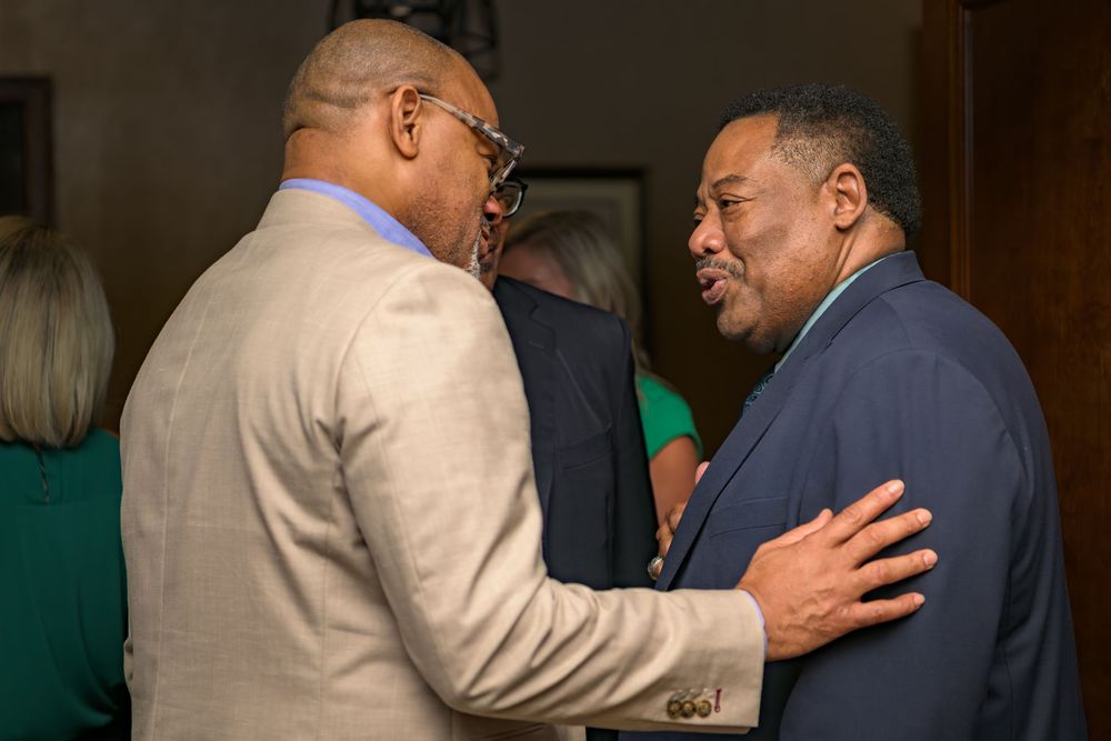 Two men in business attire having an engaged conversation at an indoor event.