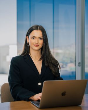 Professional woman works on laptop in modern office with city view.
