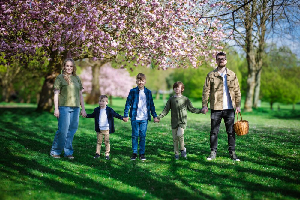 Family standing together beneath blooming cherry blossoms on a sunny spring day.
