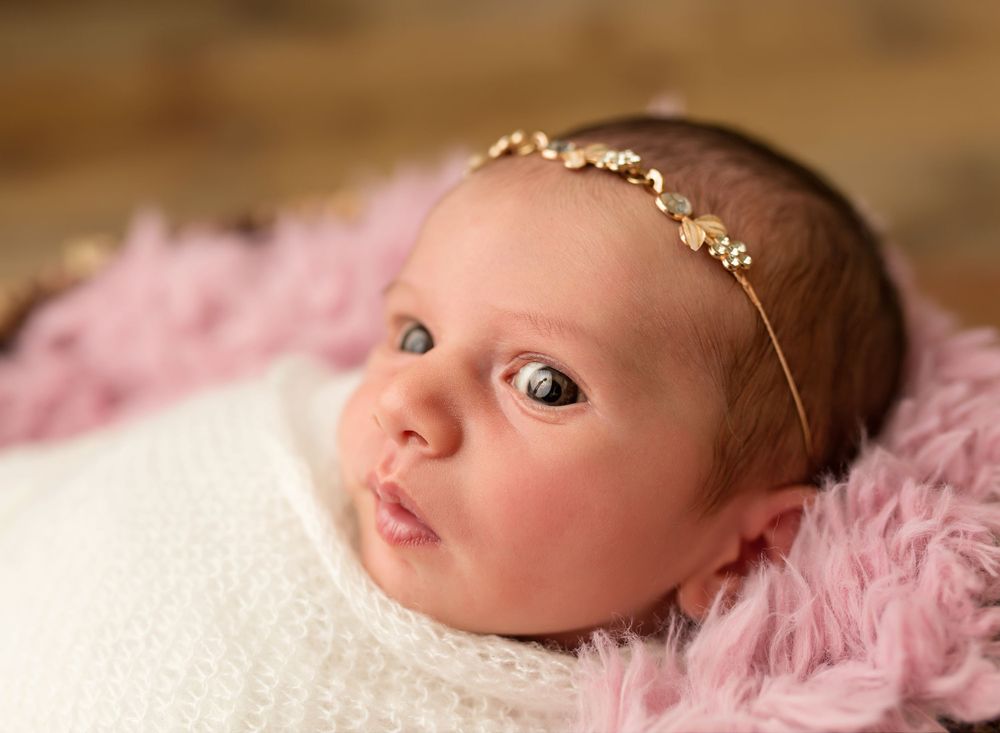 close up photo of newborn baby on a pink rug with eyes open