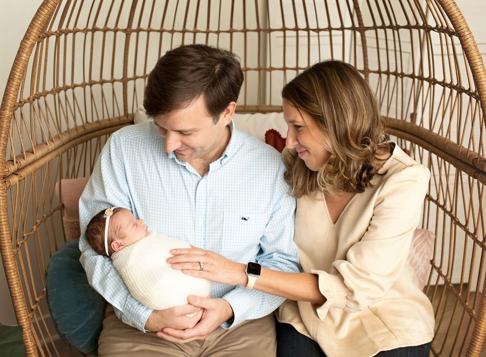 family photo with mom, dad and newborn baby wrapped in white wrap