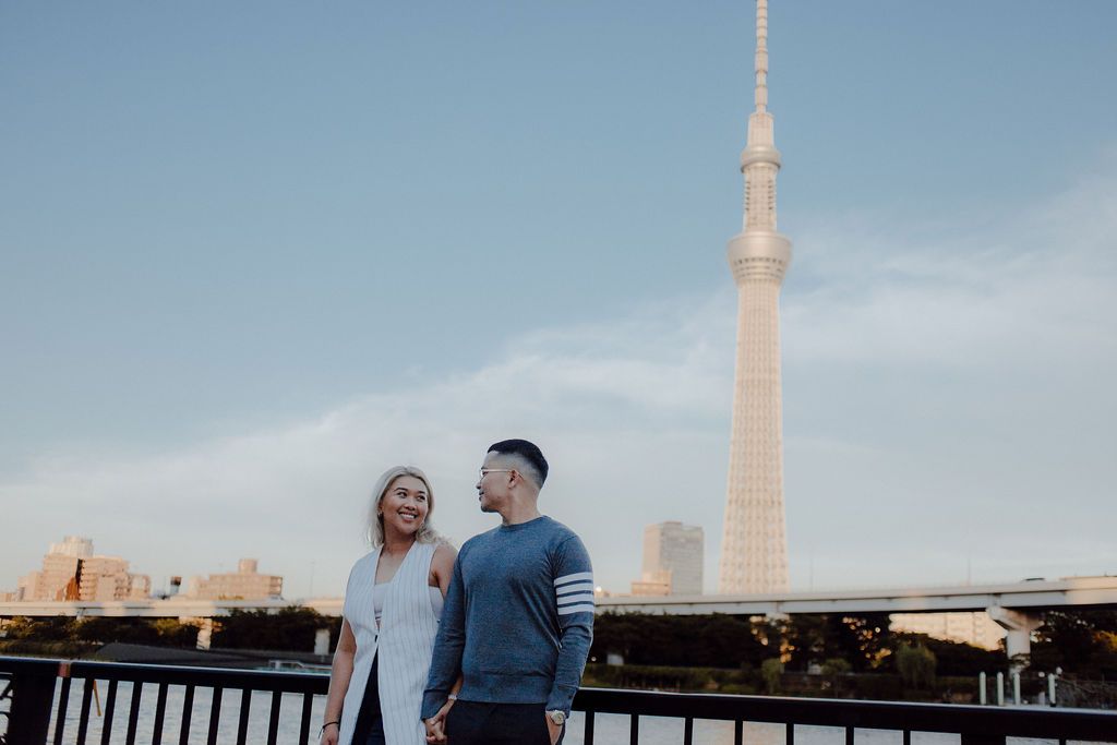 Couple standing on a viewing platform with the Tokyo Skytree tower visible in the distance.